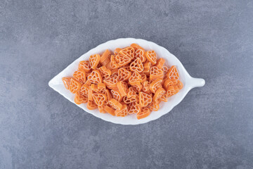 Uncooked heart-shaped pasta on leaf-shaped plate