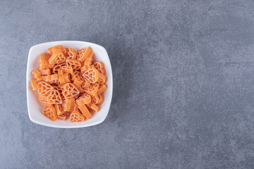 Pile of heart-shaped pasta in white bowl
