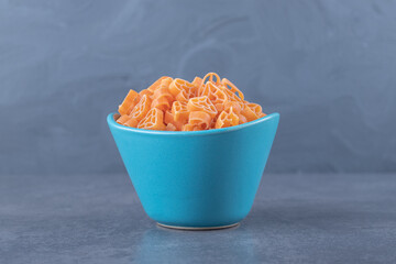 Dry heart-shaped pasta in blue bowl