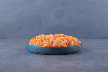 Pile of heart-shaped pasta on blue plate