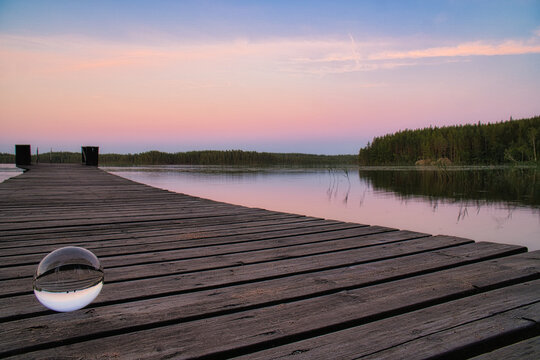 Glass ball on a wooden pier at a Swedish lake at evening hour. Nature Scandinavia