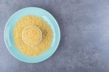 Heap of raw macaroni on blue plate