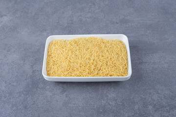 Plate of raw macaroni on stone background