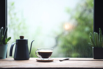coffee glass cup and blue drip pot on wooden table in front of window