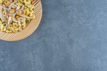 Delicious pasta with chopped chicken on wooden plate
