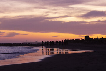 Silhouette of young fitness boy of a soccer team jogging, running at sunrise beach 