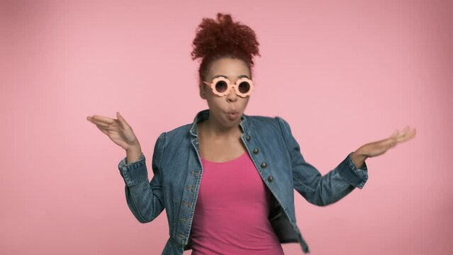 Young woman with funny glasses and casual clothes dance fool around have fun gesticulating with hands enjoy relax isolated on pink background