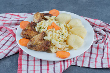 Roasted chicken wings and pasta on white plate