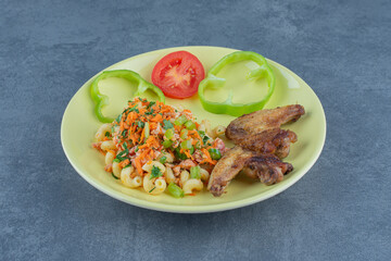 Tasty pasta and chicken wings on yellow plate