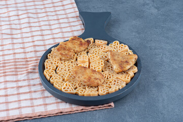 Delicious pasta with nuggets on black board