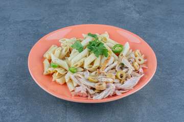 Penne pasta with chicken on orange plate