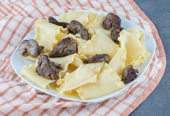 Boiled dough with dried meat parts on white plate
