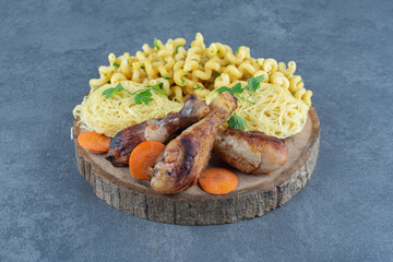 Fried legs, macaroni and spaghetti on wood piece