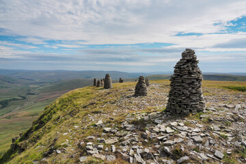 Multiple cairns standing tall at the summit of High White Scar, next to Wild Boar Fell, overlooking the Eden Valley, Cumbria, UK - obrazy, fototapety, plakaty