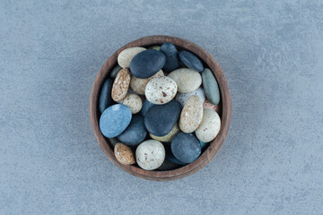 Pebble stone candies in a bowl, on the marble background