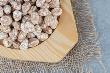 Confectionery in the wooden plate, on the trivet, on the marble background