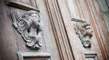 Sculpture of an old wooden angel against a wooden door of a church - more than 100 years old