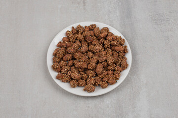 Pile of candies with sesame seeds on white plate