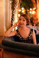Woman in 1920 style clothes with a glass. Beautiful girl retro flapper style retro vintage roaring...