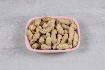 Tasty raw peanuts in pink bowl