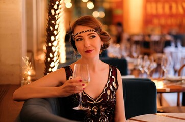 Woman in 1920 style clothes with a glass. Beautiful girl retro flapper style retro vintage roaring...