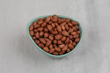 Unpeeled organic peanuts in blue bowl