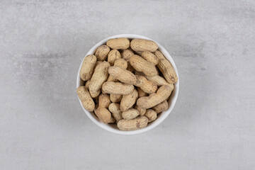 Bowl of shelled peanuts on marble background