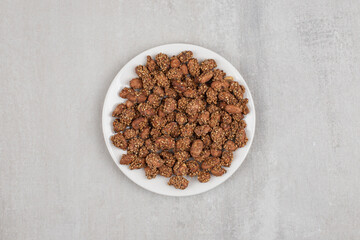Pile of candies with sesame seeds on white plate