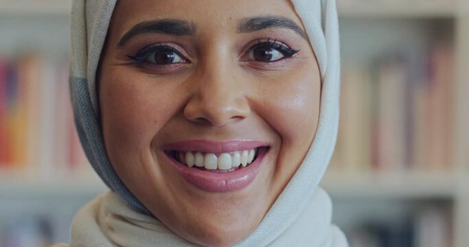 Muslim arab woman face, portrait and smile from Saudi Arabia wearing traditional headscarf, hijab and islamic religion. Happy, holy and young arabic student studying, learning and university library