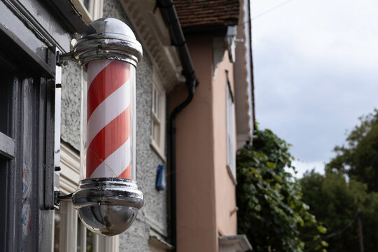 Barber's pole mounted to the wall above a barbershop in the United Kingdom, on white background