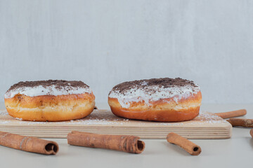 Chocolate doughnuts with cinnamon sticks on a wooden board