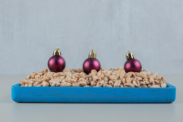 A blue wooden plate full of healthy cereals with Christmas balls