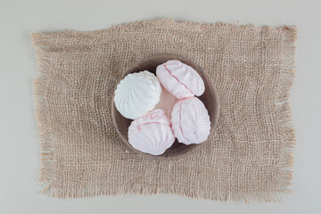 A wooden bowl full of white and pink zephyrs