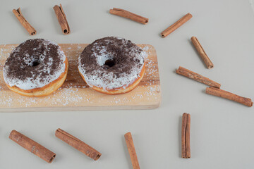 Chocolate doughnuts with cinnamon sticks on a wooden board