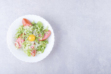 Sliced smoked sausages, lettuce and egg yolk in white bowl