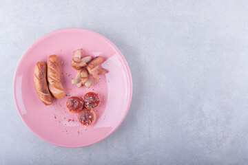 Obraz na płótnie Canvas Various shaped fried sausages on pink plate