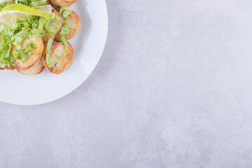 Fried potatoes garnished with lemon on white plate