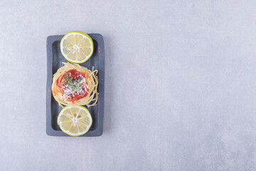 Obraz na płótnie Canvas Spaghetti with tomato pasta and lemons on dark plate