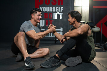 Naklejka premium Muscular man athlete in sportswear relaxing and handshake with friend after exercises at fitness gym. Workout for good health concept.