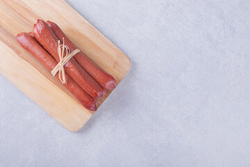 Smoked sausages tied with rope on wooden board