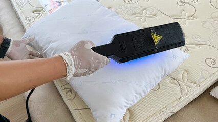 Close-up service staff is cleaning, sanitizing and banishing dust mites in a pillow and mattress...