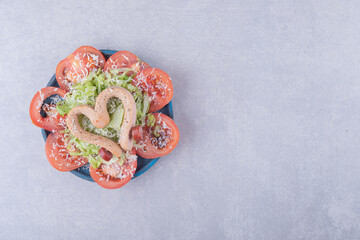 Boiled sausages shaped like heart and tomato slices