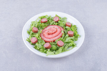 Smoked meat rolls and sliced sausages on white plate
