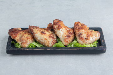 A wooden board of chicken fried meat with lettuce