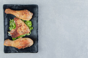 A black plate of fried meat and sliced lettuce