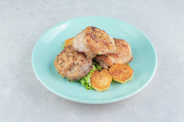 A blue plate of meat with fried sliced potatoes and lettuce