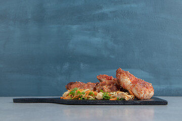 A wooden board with fried meat and vegetable salad