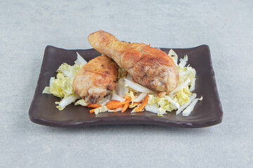A black plate with fried meat and vegetable salad