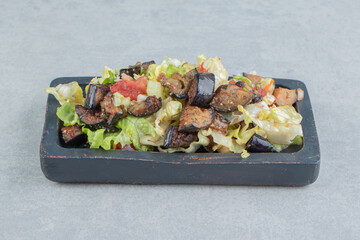 A wooden board with vegetable salad and fried eggplant