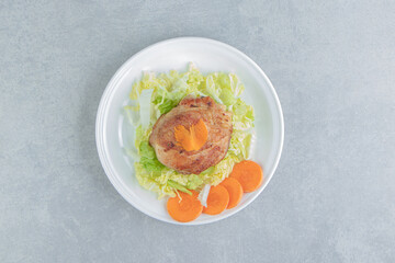 A white plate of chicken fried meat and sliced carrot
